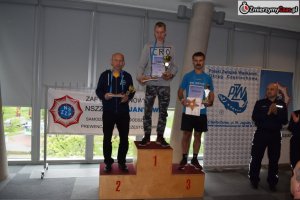 uczestnicy XI Marszobiegu Policji w Częstochowie - wręczanie nagród i medali. 3 zwycięzców stoi na podium z pucharami medalami