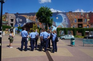 grupa studentów z Niemiec stoi tyłem do fotografa i patrzy na mural znajdujący się na budynku przy Dworcu PKP