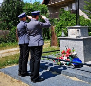 dwóch policjantów salutuje przed pomnikiem
