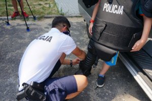 policjant pomaga chłopcu włożyć ochraniacze na nogi