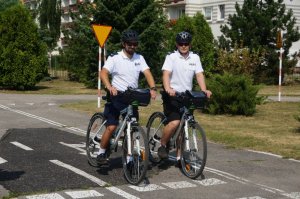 dwóch policjantów na rowerach pozują do zdjęcia