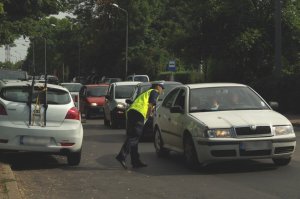 policjantka w kamizelce odblaskowej rozmaiwa z kierowcą samochodu przez uchyloną szybę