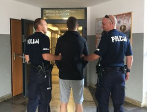 policjanci na korytarzu prowadzą zatrzymanego męzczyznę