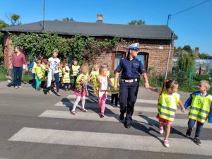 policjantka która przeprowadza grupę dzieci przez przejscie dla pieszych