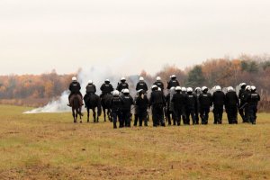 konie policyjne przechodzące przez chmurę dymu, za nimi ustawiony podoodział policji