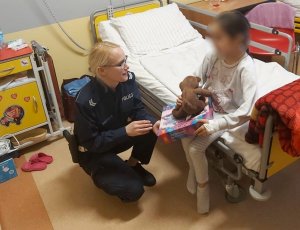 policjantka rozmawia z dziewczynką siedzącą na łóżku szpitalnym