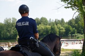 policja konna patroluje teren przy akwenie wodnym
