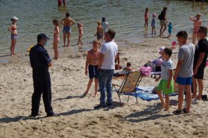 policjant na plaży rozmawia z plażowiczami