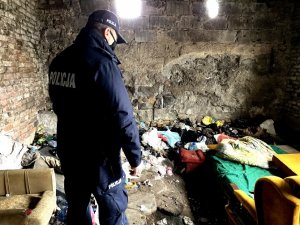 policjant podczas sprawdzenia pustostanu, gdzie znajduje się stara kanapa i śmieci