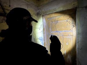 policjantka świeci latarką na drzwi opuszczonego lokalu