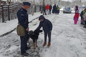 policjant z psem służbowym - obok stoi dziecko, które głaszcze psa
