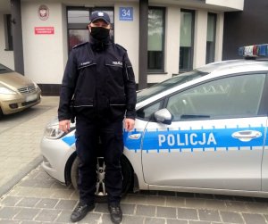 policjant w mundurze stoi przy radiowozie przed Komisariatem w Kłomnicach