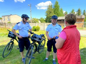 policjanci na rowerach rozmawiają z kobietą podczas obchodu swoich rejonów słuzbowych