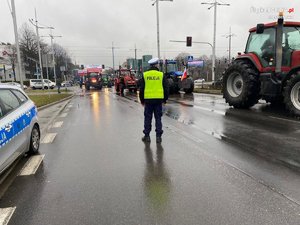 Policjant zabezpiecza przejazd ciągników rolniczych przez jezdnię